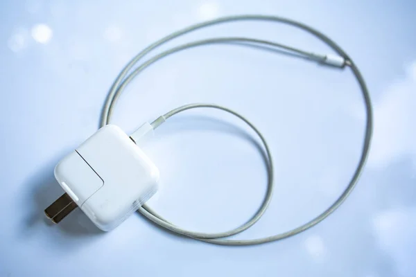 Τροφοδοτικό USB για συσκευές, καλώδιο φορτιστής σε λευκό ακρυλικό φόντο τραπεζιού, κοντινό πλάνο και στιγμιότυπο, επιλεκτική εστίαση, τεχνολογία, επιχειρηματική έννοια — Φωτογραφία Αρχείου