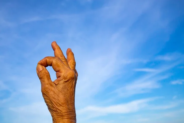 Símbolo de la mano derecha de la mujer mayor que significa "OK" en el fondo azul del cielo, parte asiática de la piel del cuerpo, Símbolo, Gestos, Concepto de lenguaje corporal — Foto de Stock