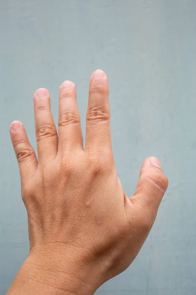 女性の背中の左手の親指指のトリガーフィンガーロック,痛みに苦しむ, 青灰色の背景に, クローズアップ & マクロショット, オフィス症候群, ヘルスケアコンセプト — ストック写真