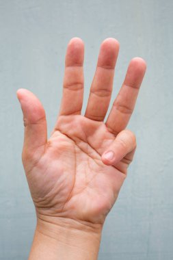 Tetik Parmak kilit kadının ön sol elinin küçük parmağında, Ağrı muzdarip, Mavi-gri renk arka plan, Close up & Macro shot, Office sendromu, Sağlık kavramı