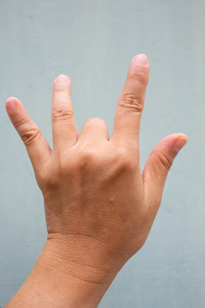 Trigger Finger lock on middle finger of woman's back left hand, Suffering from pain, On Blue-grey colour background,  Close up & Macro shot, Office syndrome, Health care concept