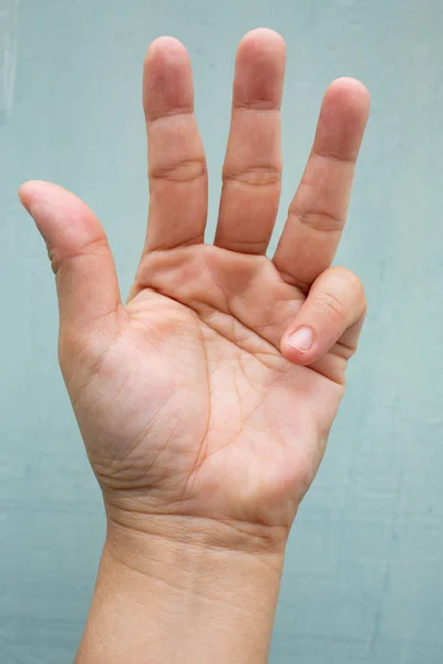 Spust palec blokada na małym palcem kobiety przedniej lewej dłoni, cierpiących na ból, na niebiesko-szary kolor tła, zbliżenie & makro strzał, zespół biurowy, koncepcja opieki zdrowotnej — Zdjęcie stockowe
