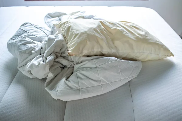 Bíle zmačkané prostěradlo, polštář slonovinové polštáře na bílé posteli, uzavření záběru, selektivní zaměření, koncepce čištění ložnice — Stock fotografie