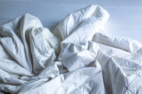 Sábana blanca arrugada en cama blanca, Primer plano, enfoque selectivo, concepto de limpieza de dormitorios — Foto de Stock