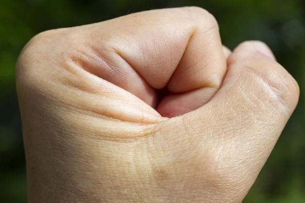 Vrouw hand met gebalde vuist in groene tuin, close-up & macro shot, selectieve focus, lichaamsdeel — Stockfoto