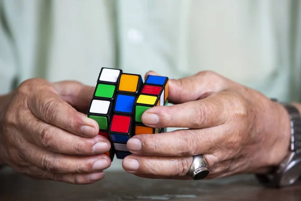 Bangkok, Thaïlande, 23 mars 2019, Vieil homme tenant le cube de Rubik et jouant avec, sur fond de texture en bois, le cube de Rubik inventé par un architecte hongrois Erno Rubik en 1974, Gros plan & Plan macro, Mise au point sélective — Photo