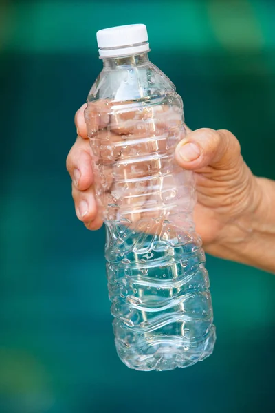 Sénior mano de la mujer aplastamiento utiliza botella de plástico, concepto de reciclaje, fondo de la piscina azul — Foto de Stock