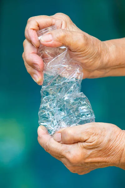 Sénior mano de la mujer aplastamiento utiliza botella de plástico, concepto de reciclaje, fondo de la piscina azul — Foto de Stock