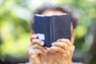 Bulanık Kıdemli kadın bokeh bahçe arka planda küçük bir lacivert renkli kitap okuma, Close up & Makro çekim, Seçici odak, Relax zaman