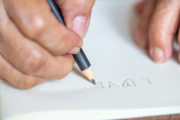 Mujer mayor derecha Escritura a mano "Amor" sobre fondo blanco, Primer plano y plano macro, Enfoque selectivo, Concepto de papelería — Foto de Stock