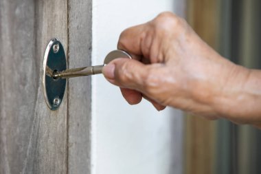 Kıdemli Kadın eli kilitlemek veya ahşap kapı kilidini açmak için bir anahtar kullanmak, Close up & Macro çekim, Seçici odak, Güvenlik kavramı