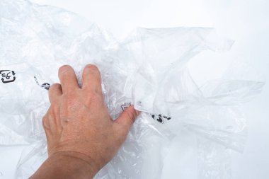 Beyaz metal arka plan, yırtık nesne, Aydınlık & Gölge üzerine sarmak için kadın sol el buruşmuş plastik paket