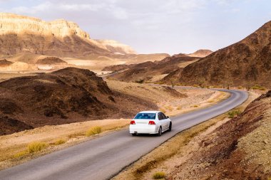 Eilat şehir, İsrail, yakın Doğu çevre Timna park kuru iki renkli kumtaşı çöl ortamındaki virajlı yolda araba.