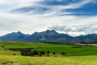Slovakya 'daki High Tatras kayalık dağlarının altındaki yeşil çayırlar. Rüzgarlı ve bulutlu bir yaz günü.