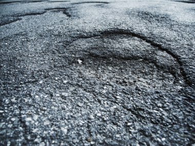 Bir yan sokakta yol bozuk asfalt zemin seviyesine ayrıntı görünümü.