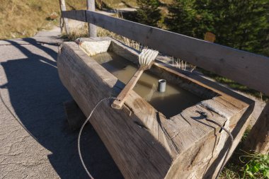 Geniş açı üzerinde temizlik için yalan yıkama fırçası ile bir ağaç gövdesi--dan oluşan bir su oluğu görünümünü Bavyera Alpleri'nde dinlenme durağında Yürüyüş botları yaz aylarında kirli..