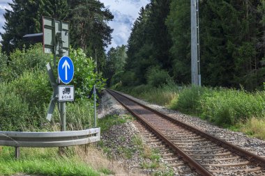 2018 yazında Bavyera 'da St. Andrew' s Cross ve Yön Oku ile demiryolu geçidi boyunca uzanan bir ormandan geçen tren yolu..