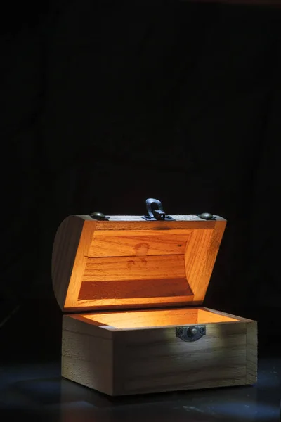 İçerideki küçük tahta sandık siyah bir arkaplana karşı aydınlanıyor..