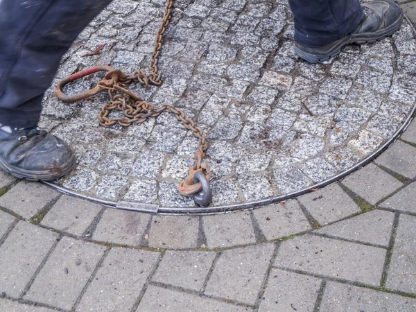 Beine auf einem schweren Kanaldeckel — Stockfoto