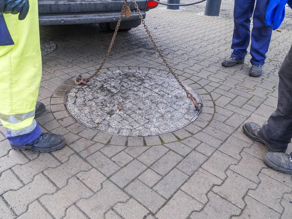 Drei Arbeiter bei der geschlossenen Mannlochabdeckung — Stockfoto