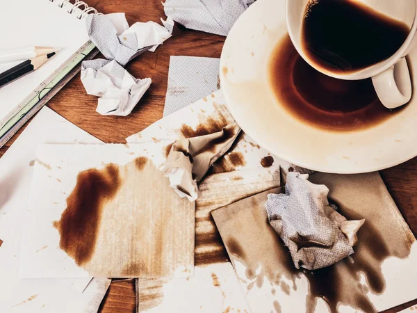 Cup of coffee spilt on wood table, top view.