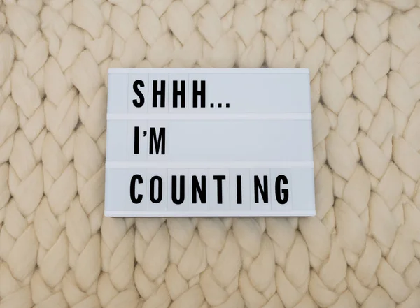 SHHH... I\'M COUNTING word on lightbox on knit background. Cozy compozition. Knit wool background.