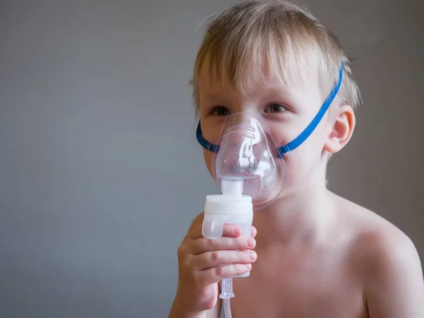 Child making inhalation with mask on his face. Asthma problems concept