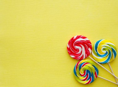 Sarı arka plan üzerinde farklı lezzetli renkli şekerler