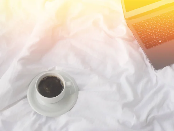 Cup of coffee on bed, top view