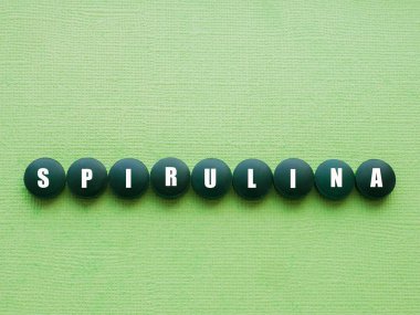 Üst ten yeşil arka plan üzerinde Spirulina yosun tabletleri