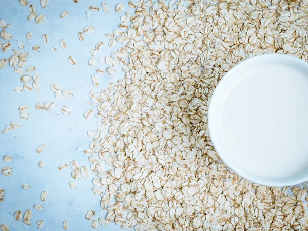 Oat milk drink in white cup and cereal flakes on kitchen bench. Flat lay. Copy space.