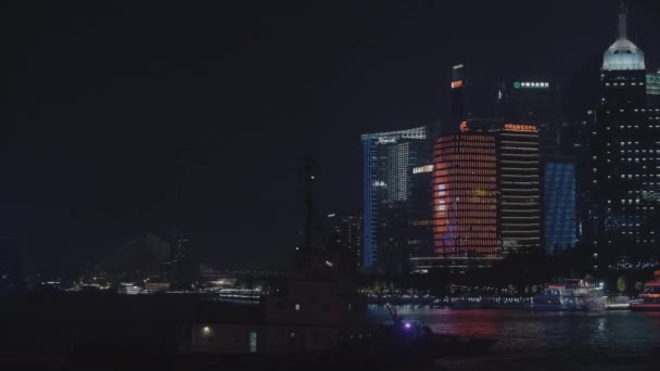 Drapacze chmur i łódź pływająca nocą po rzece w Szanghaju — Wideo stockowe