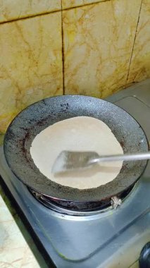 Mute vertical clip: roti/chapati cooks on a hot tawa over a gas stove and is flipped with a metal spatula. Clean flatbread preparation,great for recipe intros, reels, shorts and cooking projects.