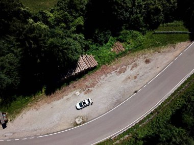 Yol kenarındaki ormanda park halindeki bir arabanın insansız hava aracı fotoğrafı.