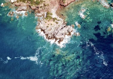 Dalgalar Sveti Stefan Montenegro 'daki kayalara çarparken denizin yukarısından bir drone fotoğrafı