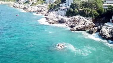Dobra Voda Karadağ 'da dalgalı deniz ve dalgalı küçük taş plajlarda denizden sakin bir drone videosu