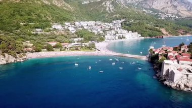 Sahildeki denizden ve Sveti Stefan körfezinden güzel mavi suyu ve Karadağ 'daki Sveti Stefan adasından bir drone videosu.