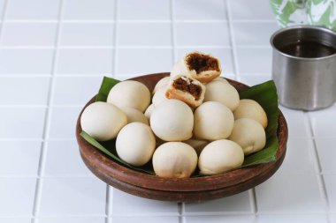 Nopia, Indonesian traditional snack filled with sweet palm sugar, served on wooden plate with banana leaf. Local Asian dessert.