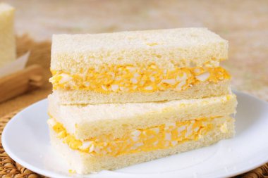 Close up of Japanese Tamago Sando sandwich with soft white bread and creamy egg filling on plate.