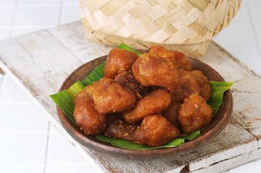 Fried cassava snack Getuk Goreng, golden brown fritters served on rustic plate with banana leaf decoration.