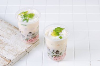Traditional Indonesian iced dessert drink Es Teler with creamy base, avocado, coconut, grass jelly, jackfruit, and sago pearls. Popular tropical street food.