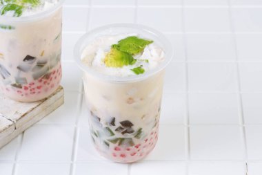 Traditional Indonesian iced dessert drink Es Teler with creamy base, avocado, coconut, grass jelly, jackfruit, and sago pearls. Popular tropical street food.