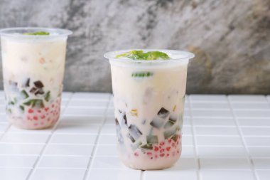 Traditional Indonesian iced dessert drink Es Teler with creamy base, avocado, coconut, grass jelly, jackfruit, and sago pearls. Popular tropical street food.