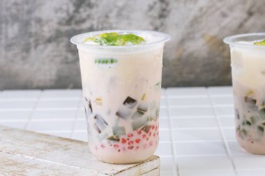 Traditional Indonesian iced dessert drink Es Teler with creamy base, avocado, coconut, grass jelly, jackfruit, and sago pearls. Popular tropical street food.