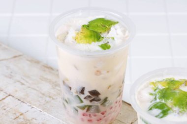 Traditional Indonesian iced dessert drink Es Teler with creamy base, avocado, coconut, grass jelly, jackfruit, and sago pearls. Popular tropical street food.