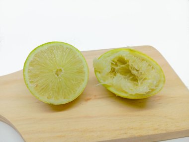 Taze bir misket limonu ve sıkılmış limonu hafif bir ahşap kesme tahtasına yan yana koyun..