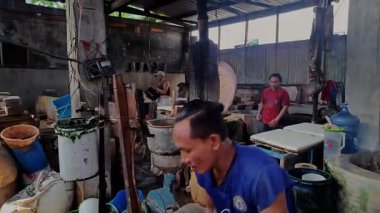 Kediri, Endonezya 13 Haziran 2024. Bir erkek işçinin geleneksel bir sepetten öğütme makinesine sırılsıklam soya fasulyesi döktüğü yakın plan video görüntüleri. Geleneksel tofu yapmak için bir malzeme..