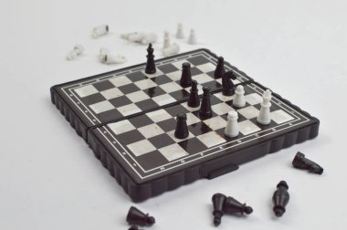 Devam eden bir oyun ve strateji oyunu gösteren dağınık satranç taşlarıyla siyah beyaz bir satranç tahtası..