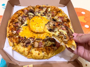 Yakın plan çekimde mantarlı, jambonlu ve erimiş peynirli bir dilim pizza karton bir teslimat kutusunda servis edilen taze fırında pizza..