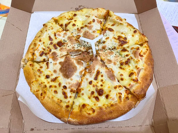 Karton teslimat kutusunda servis edilen altın hamurlu sıcak peynirli pizza. Lezzetli İtalyan fast food öğle, akşam ve parti yemekleri için popüler..